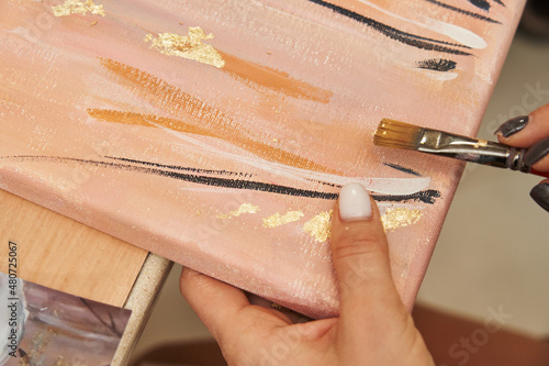 women's hands brush over a painting with gold potal photo