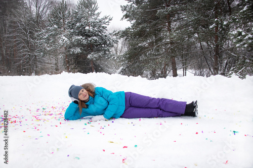 young girl lies on the snow in the village