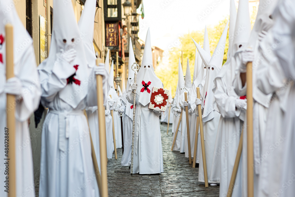 Naklejka premium The extraordinary Christian procession of the Holy Week in Granada, Andalucia, Spain. Unrecognizable people dressed as Nazarenes spreading Catholic faith in public.