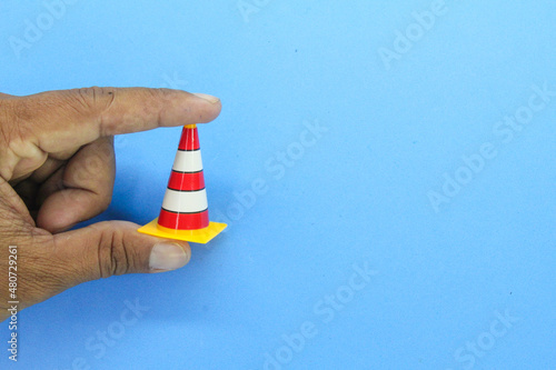 hands holding red, white and yellow construction cones. construction site concept