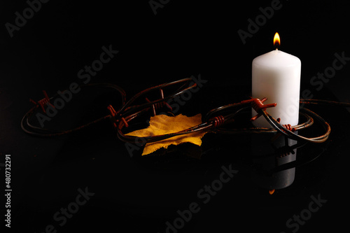 Holocaust memory day. Arbed wire and burning candle on black background photo