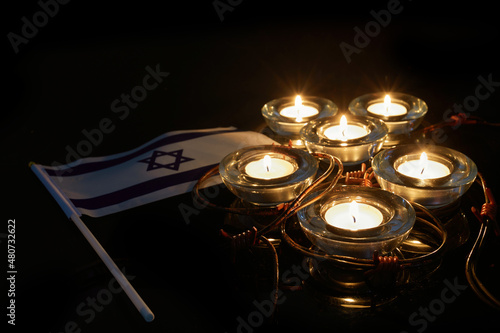 Burning candle and flag of Israel on black background. Holocaust memory day photo