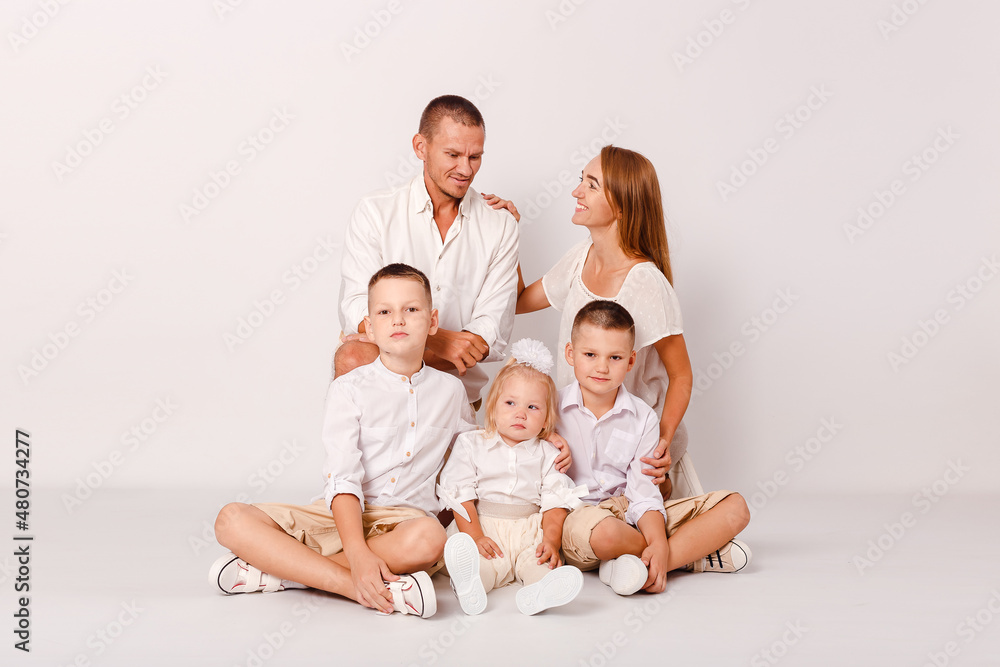 happy parents and three beautiful children embrace on a white background