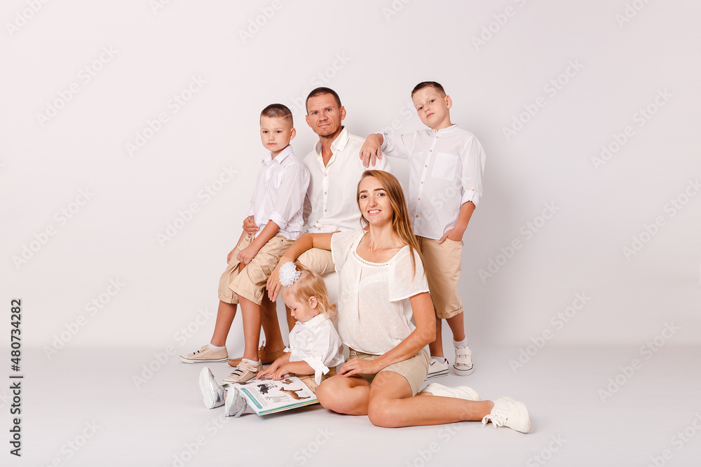 happy parents and three beautiful children embrace on a white background happy parents and three beautiful children embrace on a white background