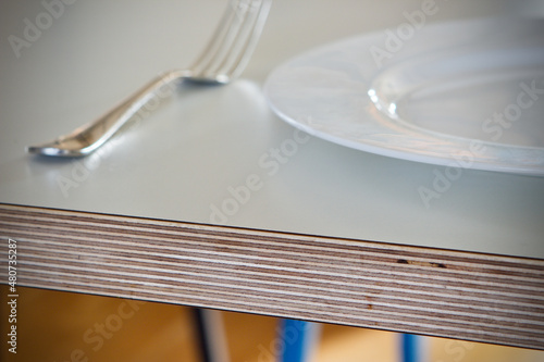 Birch plywood laminate topped table with white plate and fork close up