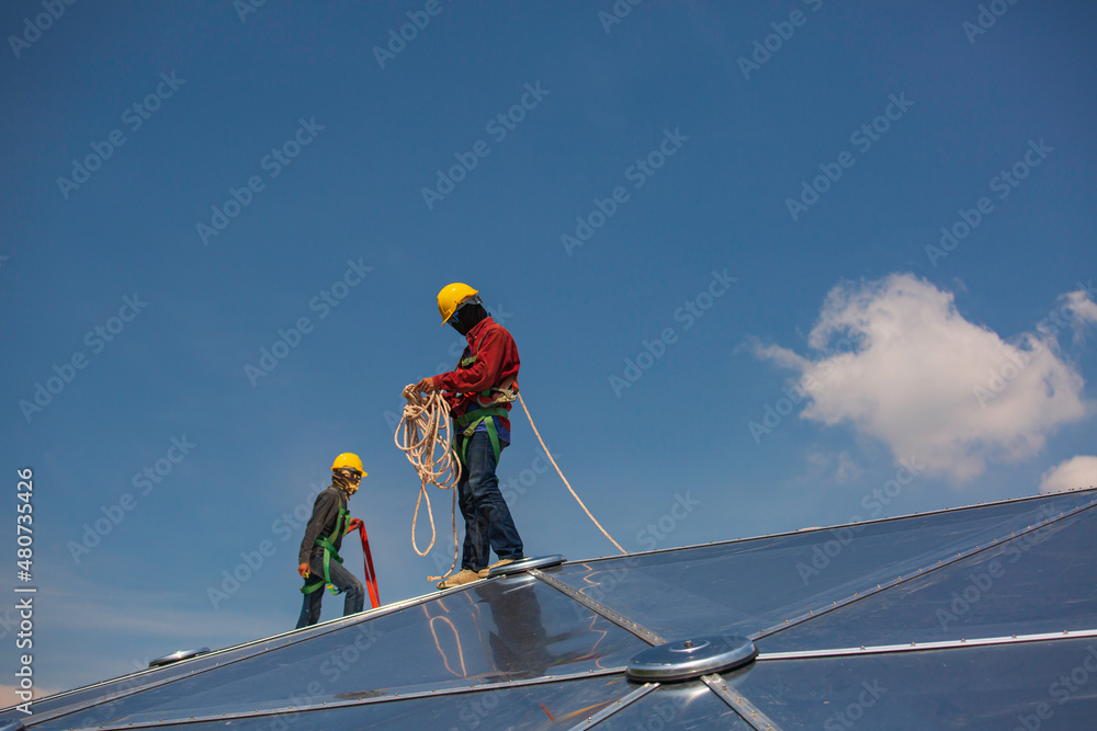 Male workers rope access height safety connecting with a knot safety harness, to ascending, construction site oil tank dome. Male workers rope access height safety connecting with a knot safety harness, to ascending, construction site oil tank dome.