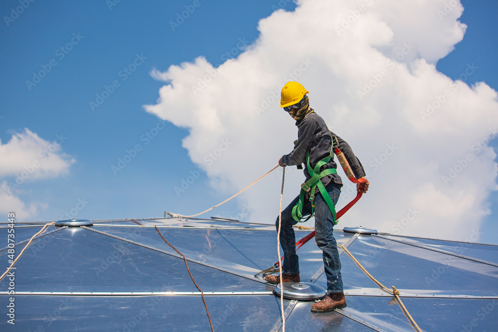 Male workers rope access height safety connecting with a knot safety harness, to ascending, construction site oil tank dome. Male workers rope access height safety connecting with a knot safety harness, to ascending, construction site oil tank dome.