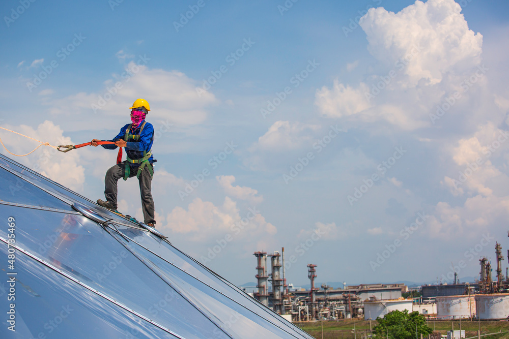 Male workers rope access height safety connecting with a knot safety harness, to ascending, construction site oil tank dome. Male workers rope access height safety connecting with a knot safety harness, to ascending, construction site oil tank dome.