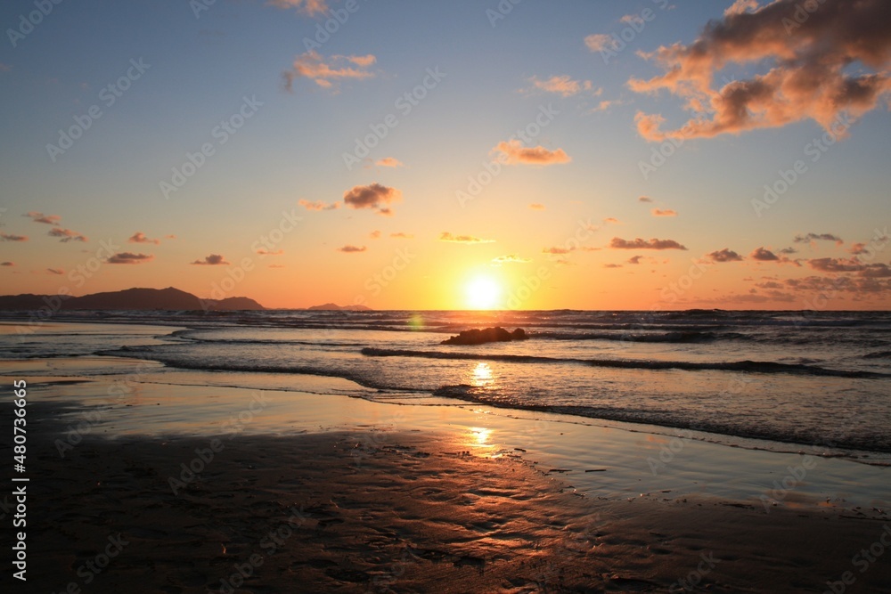 Playa de Sopelana al anochecer con el horizonte con el sol al centro a punto de esconderse