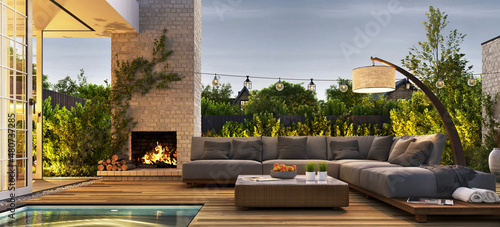 Outdoor patio area with garden furniture, swimming pool and outdoor fireplace. Evening view