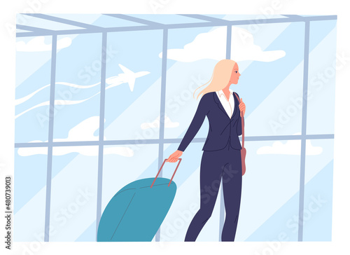Young woman walks through an airport with a suitcase
