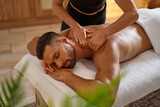Young man being massaged by masseuse at spa
