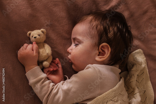 The kid sleeps sweetly with the Teddy bear