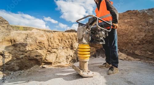 Worker uses a portable vibration rammer at construction of a power transmission substation