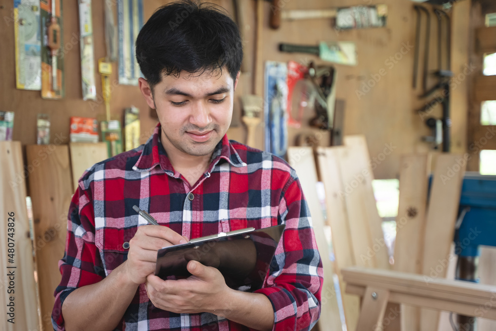 Young asian small business owner in the woodwork workshop and calling on phone with customer. Young asian small business owner in the woodwork workshop and calling on phone with customer.