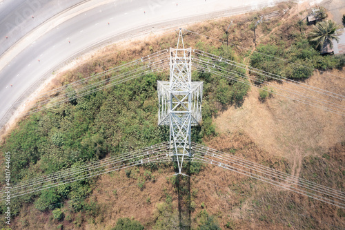 Transmission tower or pylon in aerial view. That substation, utility, infrastructure or steel structure for network of electrical grids system to carry high-voltage wire, cable or overhead power line  photo