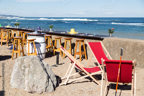Face    la mer et ses rouleaux  terrasse d un bistro pour boire et manger    l ext  rieur au soleil  assis sur des tabourets en bois.