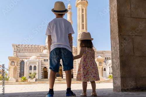 A boy and a girl standing in front of El Mustafa Mosque holding hands and looking at it. View from behind. Sharm El Sheikh, Egypt.