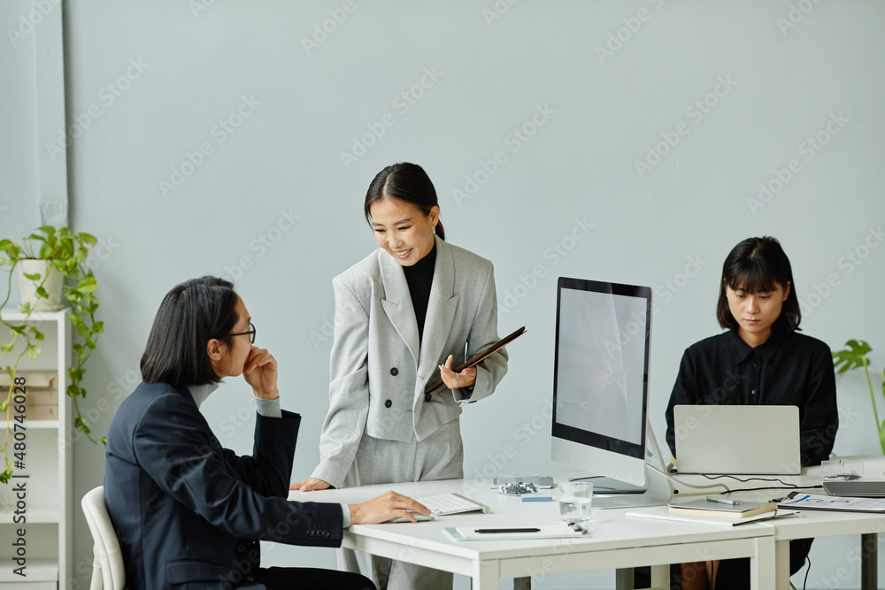 Portrait of smiling Asian businesswoman working with team of colleagues in modern office, copy space Portrait of smiling Asian businesswoman working with team of colleagues in modern office, copy space