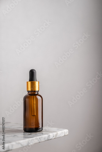 Minimalistic composition with a glass brown bottle of serum with a pipette for skin care. The concept of health and beauty. copy space