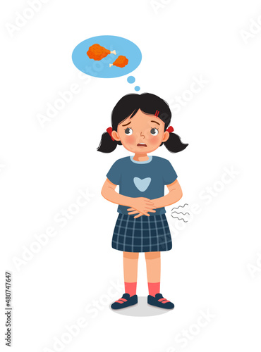 cute little girl feeling so hungry holding her stomach thinking of eating fried chicken