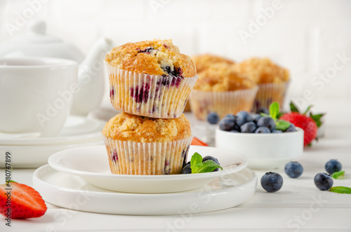 Lemon muffins with blueberries and shtreisel with fresh berries on a white wooden background. Delicious breakfast. Copy space.
