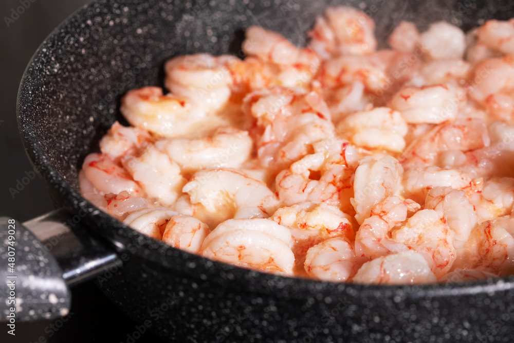 Prawns cooking. Frying pan with fried peeled shrimps spices and smoke, close up. Mediterranean, keto diet. Healthy food Prawns cooking. Frying pan with fried peeled shrimps spices and smoke, close up. Mediterranean, keto diet. Healthy food