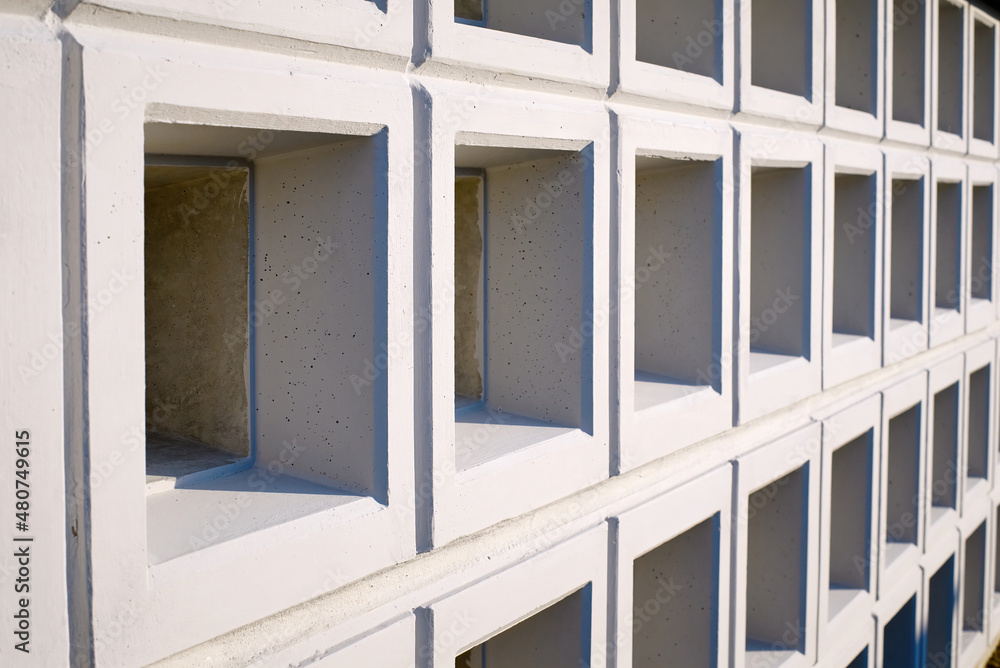 Fototapeta premium Wall with new empty cremation niches. Row with empty graves for cinerary urns. Cremation service, cemetery property. Columbarium area outside crematorium.