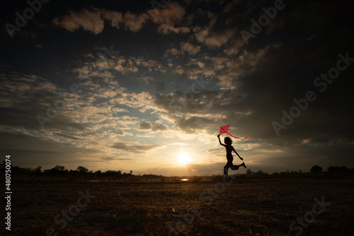 Silhouette of children flying a kite on sunset