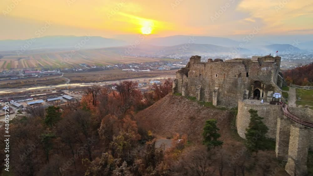 Aerial drone view of the Neamt Citadel in Targu Neamt, Romania. Fortress on the top of a hill, surrounded by lush yellowed forest, tourists, town on the background Aerial drone view of the Neamt Citadel in Targu Neamt, Romania. Fortress on the top of a hill, surrounded by lush yellowed forest, tourists, town on the background