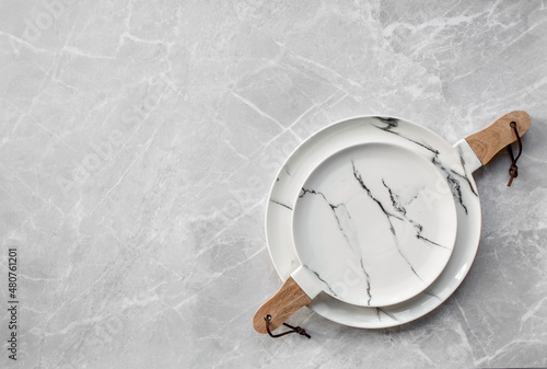 Banner. An empty ceramic marble plate with a wooden handle on the background of a gray concrete table. Space for text. Menu concept for cafes and restaurants.