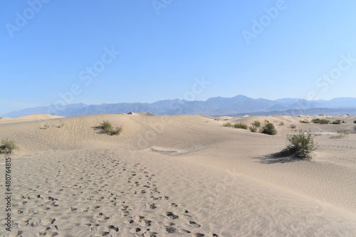 Sandy dunes with footprints and brown mountains in Death Valley desert