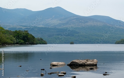 Mountains over blue glassy lake with rocks in Ireland