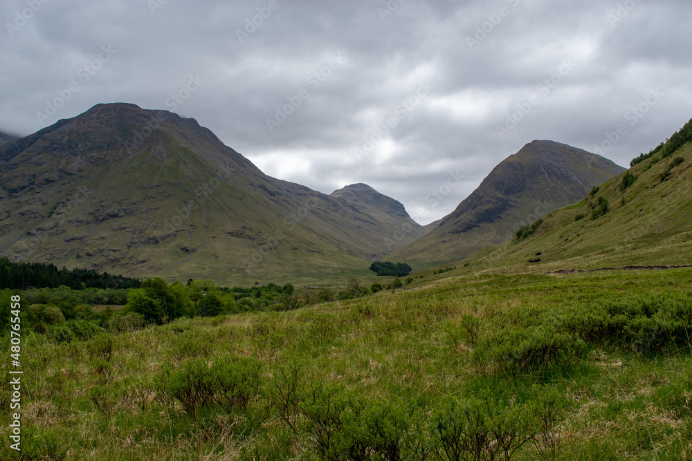Green and brown mountains in Scottish highlands with cloudy and overcast gray sky
