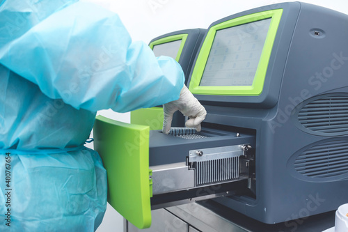 A Medical technician places Covid-19 test samples into a PCR Machine, also known a Thermal Cycler, in a cleanroom at a testing laboratory. photo