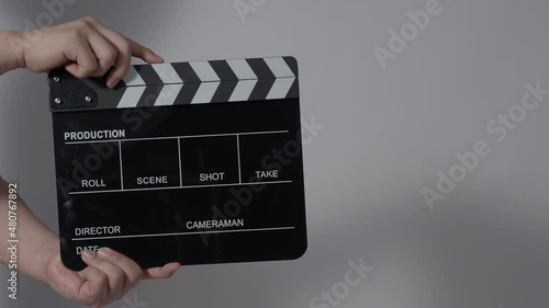 Movie slate or clapperboard hitting. Close up hand holding empty film slate and clapping it. Open and close film slate for video production. film production. color background studio. ready to shoot photo