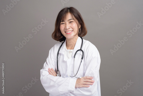 Portrait of young confident woman doctor isolated over grey background studio