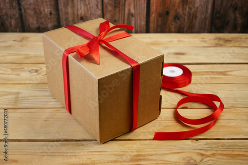 Gift parcel or mail box with ribbon red bow, brown carton parcel, surprise © lesslemon