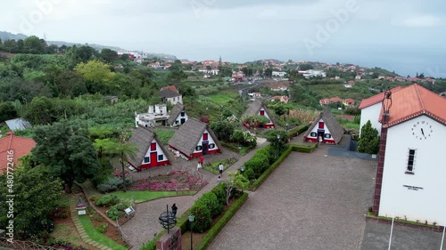 Aerial 4K footage of a drone flight over Santana village houses and city hall in Madeira, which is known for the traditional colorful homes  photo