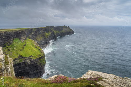 Beautiful and tall, iconic Cliffs of Moher with Moher Tower on far distance, popular tourist attraction, Wild Atlantic Way, Co. Clare, Ireland