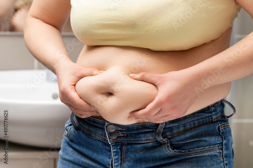 Obraz na płótnie Close up of a obese young woman checking her fats in the bathroom