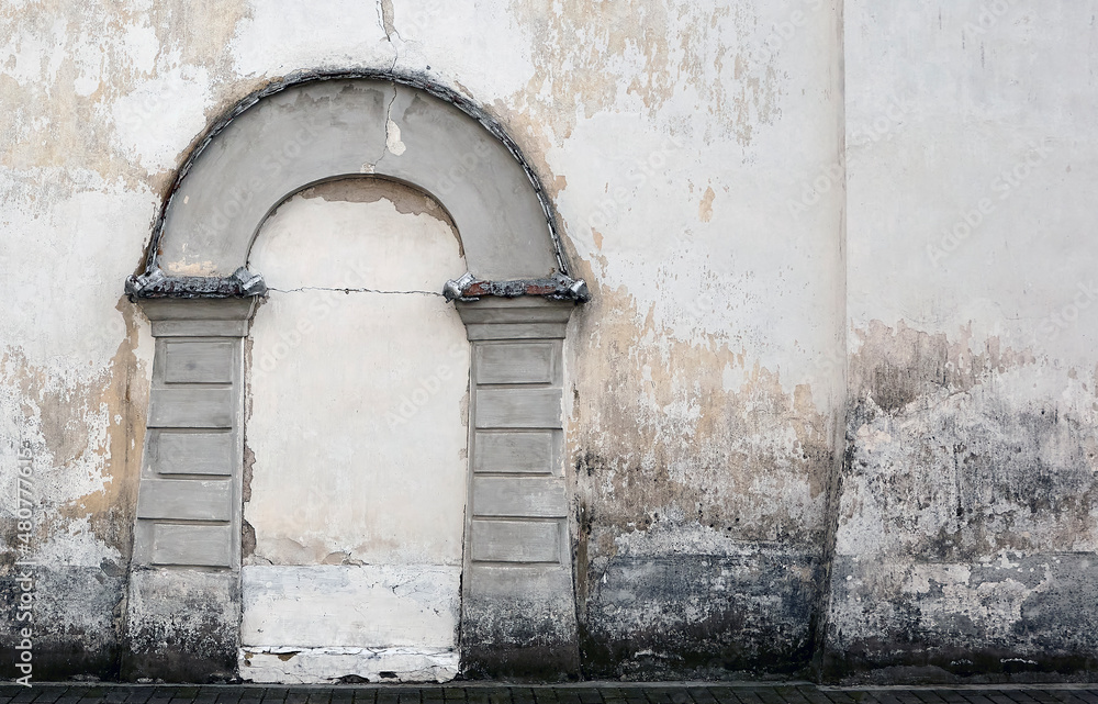 Fototapeta premium An old church wall of gray brick with a walled door on it.
