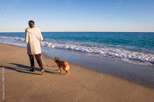 Photography young italian woman walking on the shore with her dog