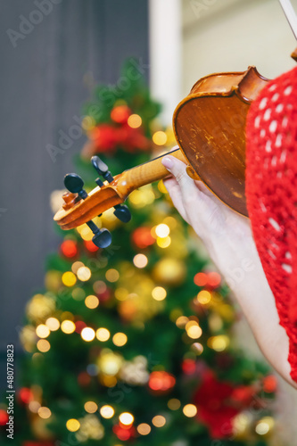young woman in red dress playing violin  rear view  background blurred
