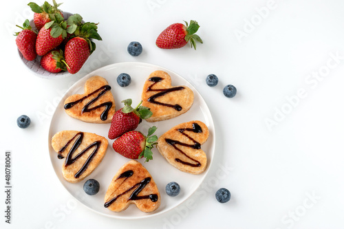 Cottage cheese pancakes in the form of hearts with strawberries and blueberries.
