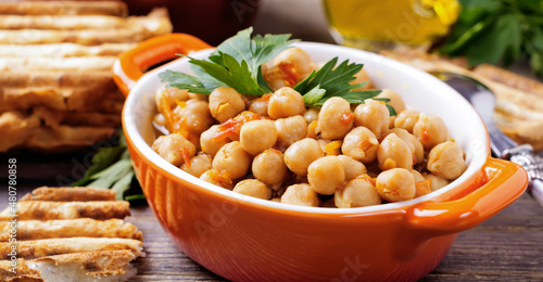 Vegetarian cooked chickpea with tomato and parsley on old wooden background. Selective focus. photo