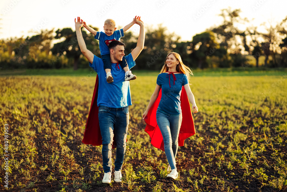 Fototapeta premium concept of european superfamily, outdoors, loving father holds on the neck, superhero family run at sunset in nature
