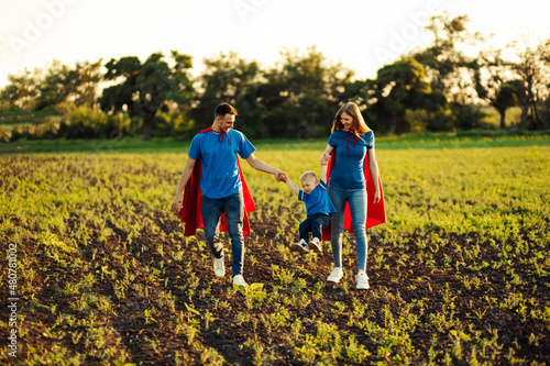 concept of european superfamily, outdoors, loving father holds on the neck, superhero family run at sunset in nature