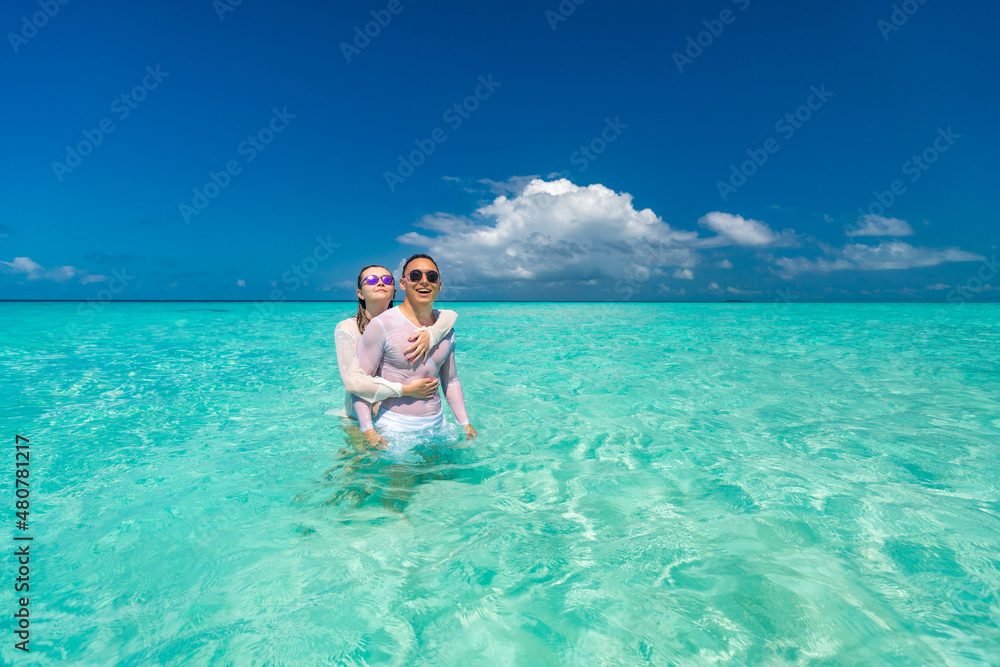 Young happy couple on tropical beach at summer vacation.