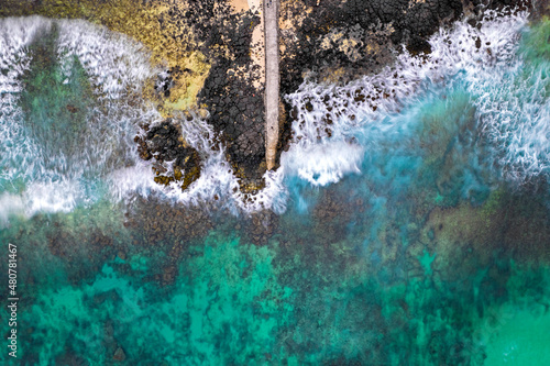 Aerial long exposure view of a fishing pier and the waves crashing on the south coast of Mauritius island
